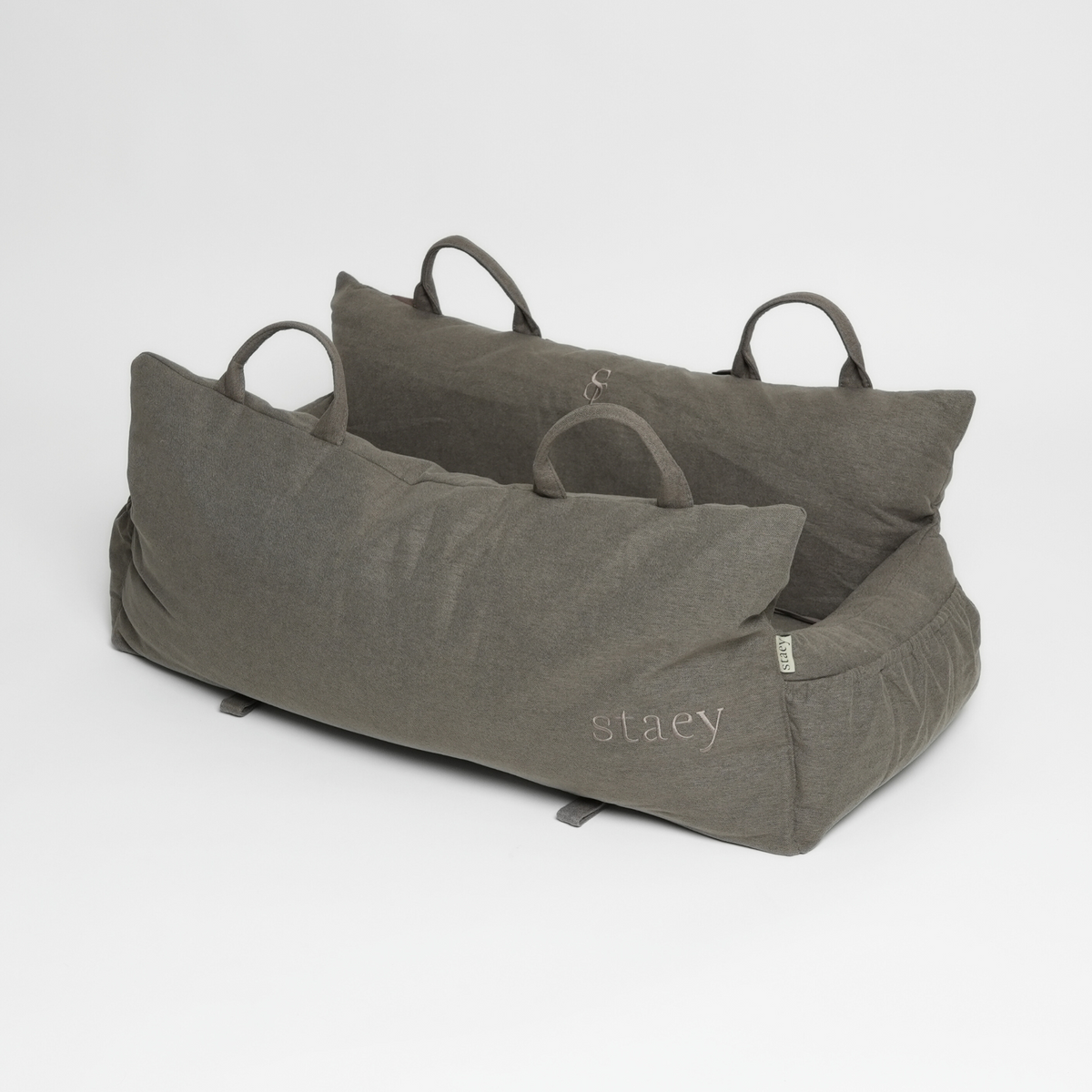 The taupe Lara XXL car seat seen at an angle with its embossed Staey mark