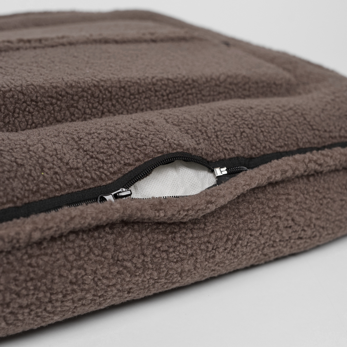 Close-up van de ritssluiting op de afneembare hoes van de taupe-kleurige teddyhondenmand