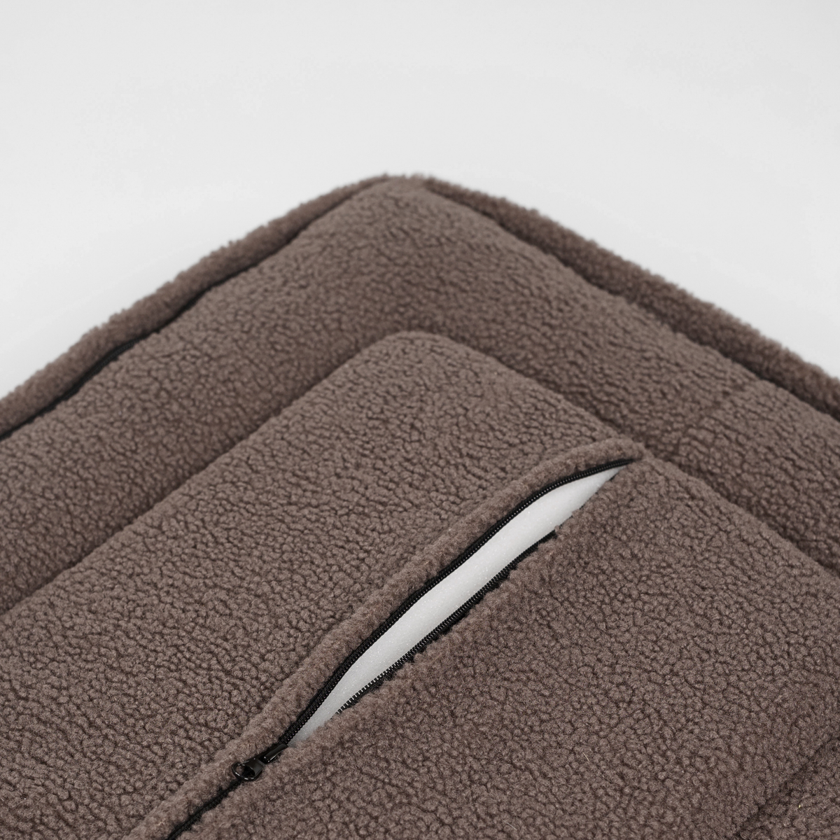 Close-up van de rits langs de rand van de taupe-kleurige teddyhondenmand
