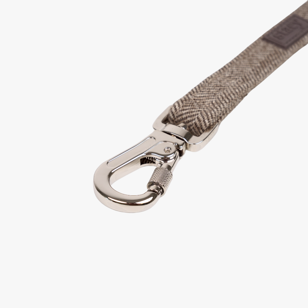 Close-up van de karabijnhaak en het Herringbone-patroon op de mokka-kleurige Elma-riem
