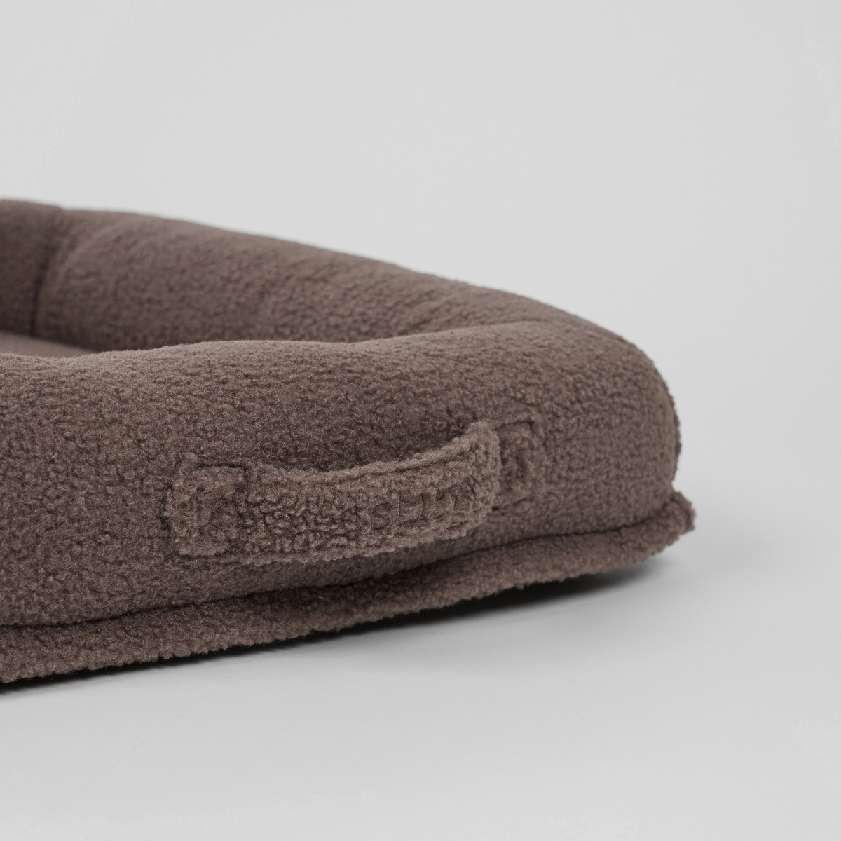 Close-up van het draaghandvat op de taupe-kleurige teddyhondenmand