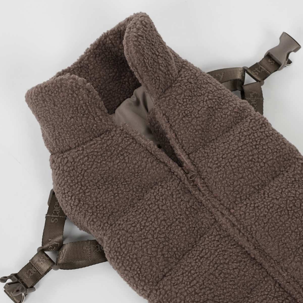 De taupe teddyhondenjas met hondentuig, plat neergelegd