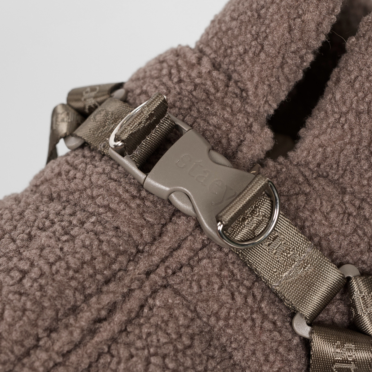 Close-up van de gesp van het harnas op het taupe-kleurige teddyhondenjasje