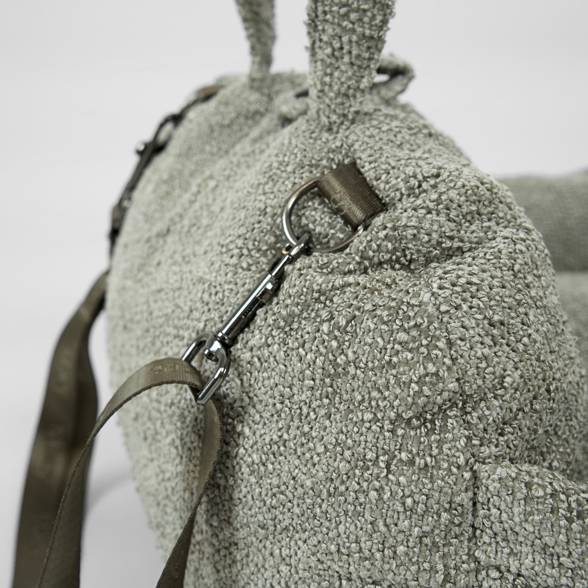Close-up of the safety leash and shoulder strap on the moss green bouclé car seat