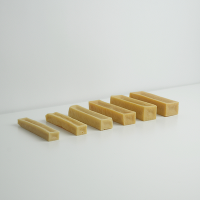 Seven natural cheese chew sticks for dogs lined up by size